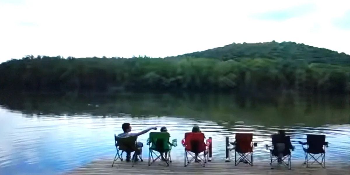 A group of people are sitting on a dock overlooking a lake.