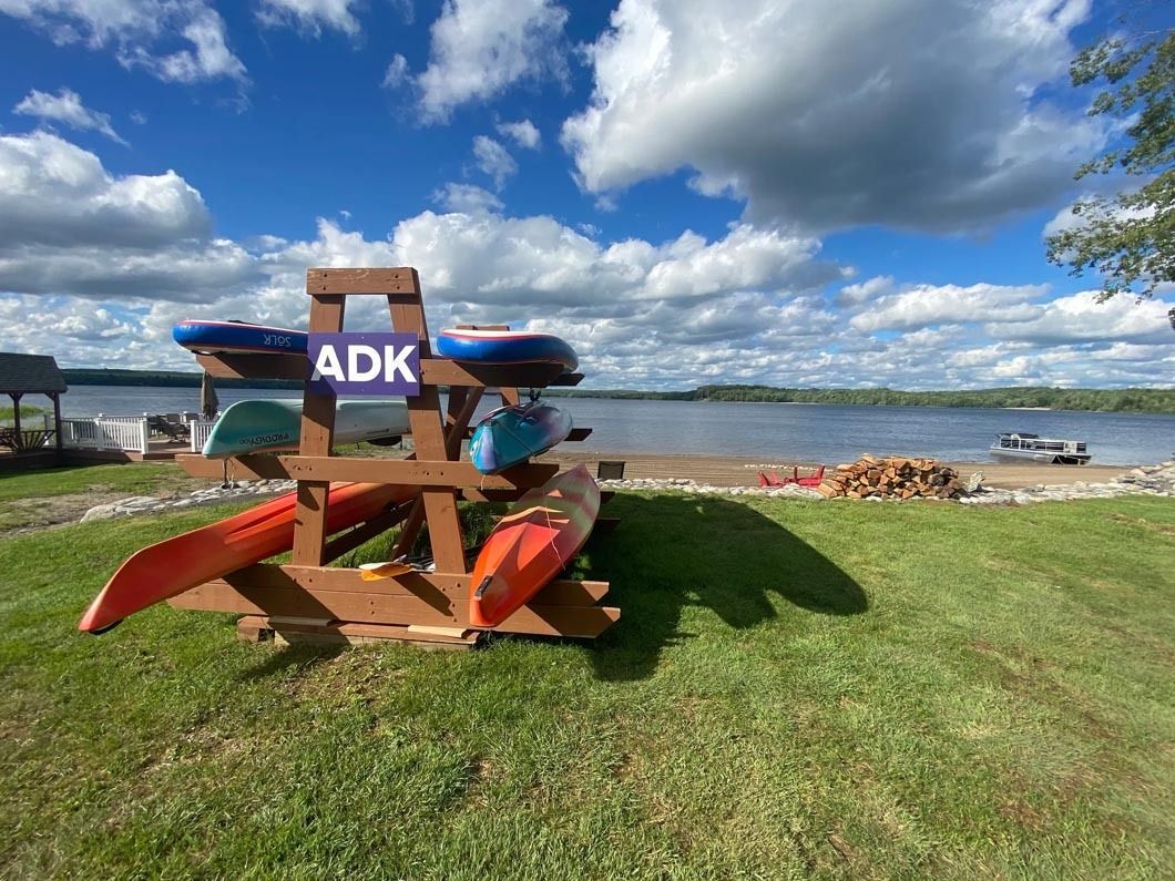 A wooden kayak rack is sitting in the grass next to a lake.