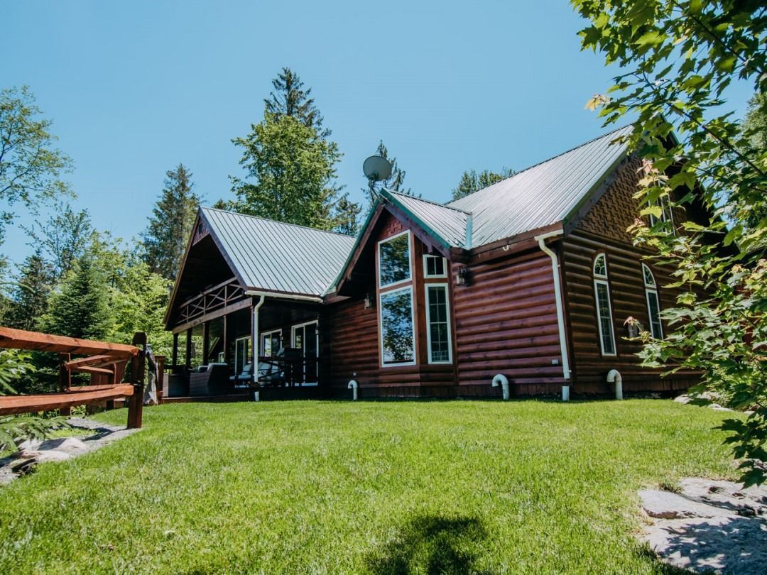 A log cabin is sitting in the middle of a lush green field.