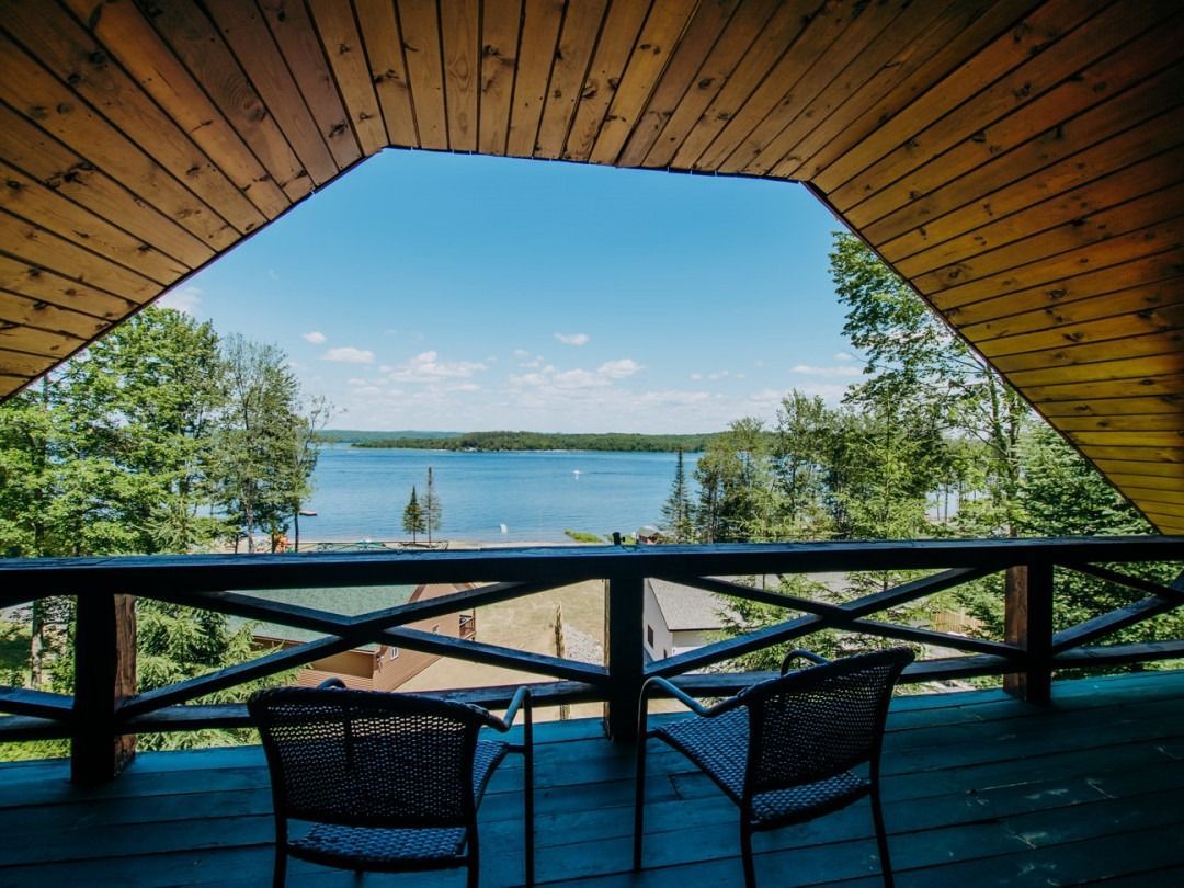 A balcony with two chairs and a view of a lake.