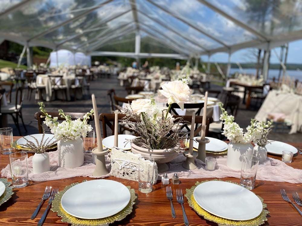 A table set for a wedding reception under a clear tent.