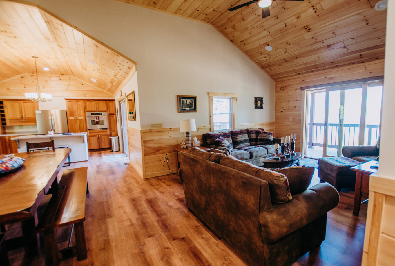 A living room filled with furniture and a vaulted ceiling in a log cabin.