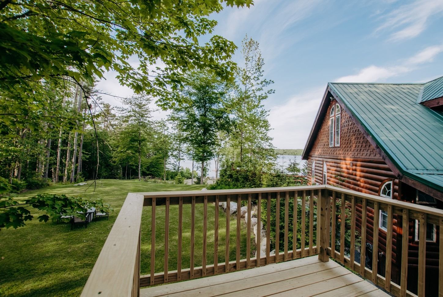 A wooden deck with a view of a house and a lake.