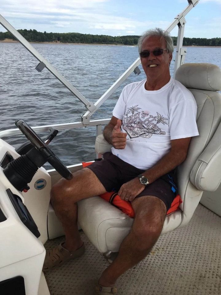 A man is sitting on a boat giving a thumbs up