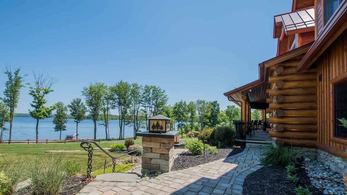 A log cabin with a walkway leading to it and a lake in the background.