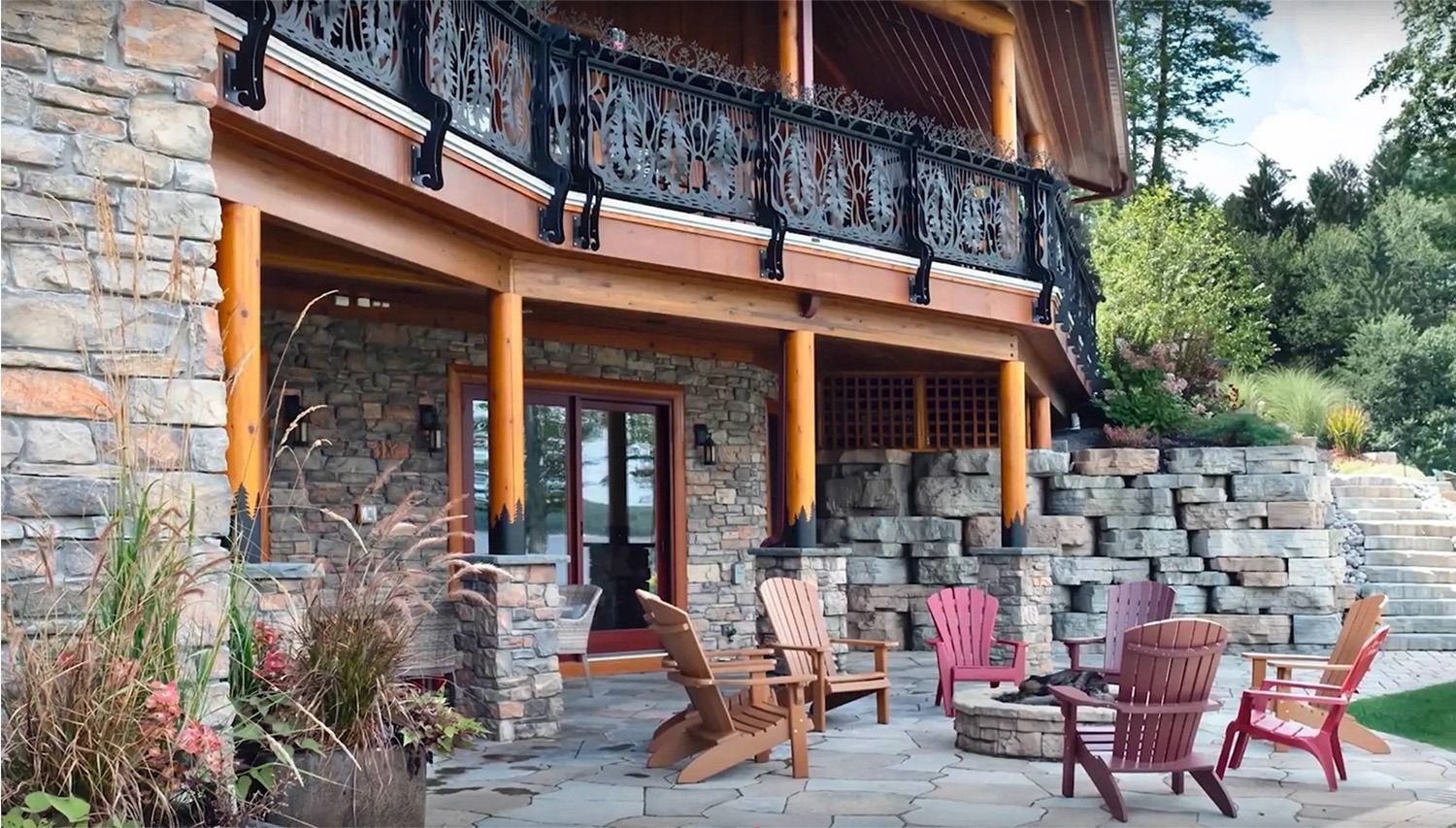 A large stone house with a patio with chairs and a fire pit.