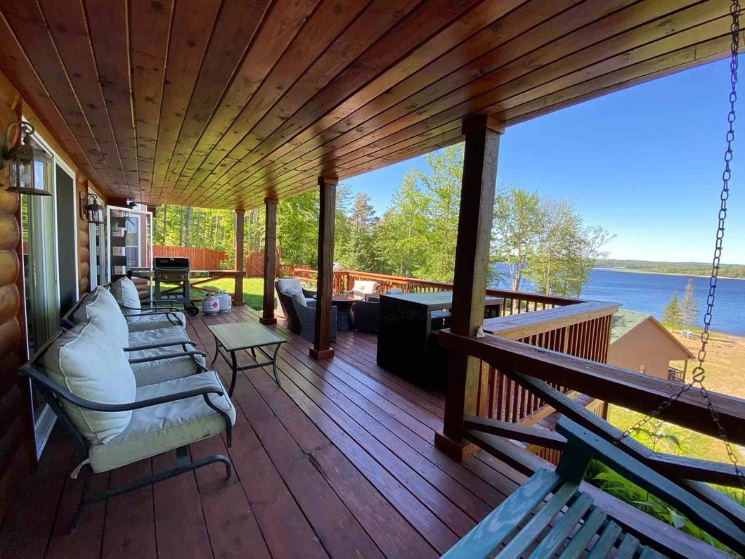 A large wooden porch with a view of a lake.