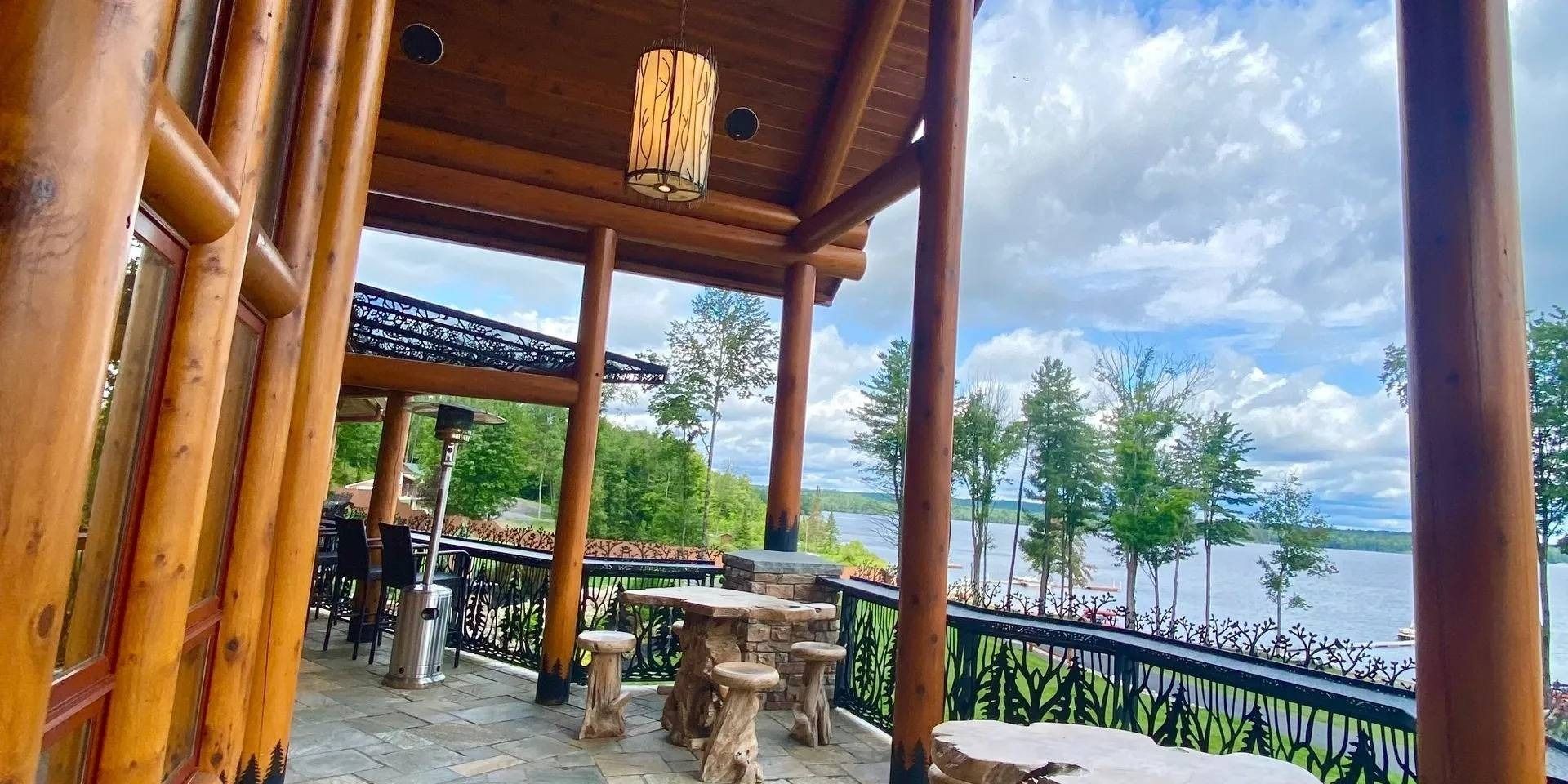 A wooden gazebo with tables and chairs overlooking a lake.