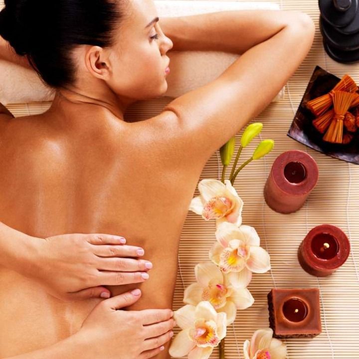 A woman is getting a massage with flowers and candles around her