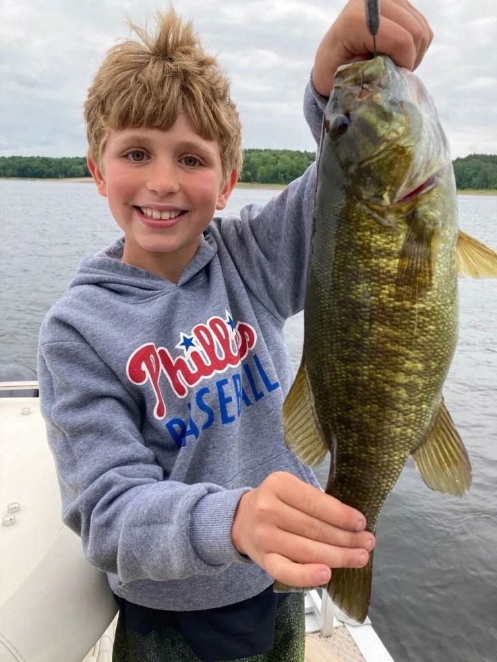 A young boy is holding a large fish on a boat.