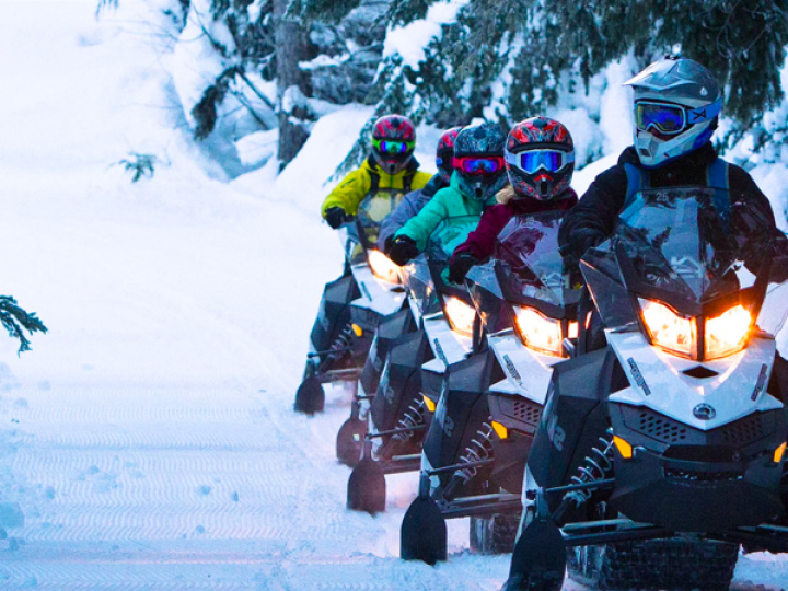 A group of people are riding snowmobiles in the snow.