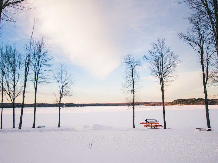 A picnic table is sitting in the middle of a snow covered field.