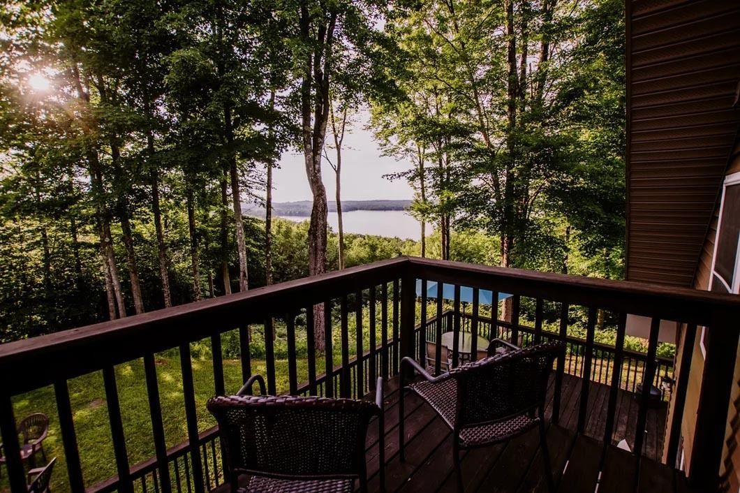 A balcony with a view of a lake and trees.