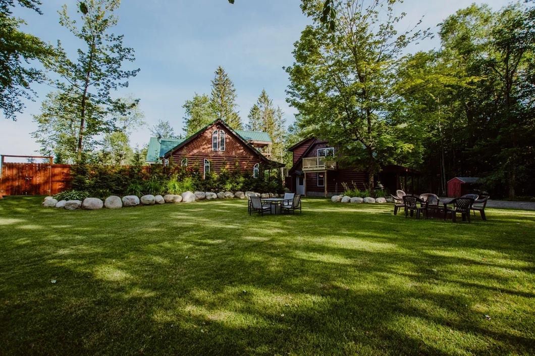 A large lawn with a house in the background and a fire pit in the middle.