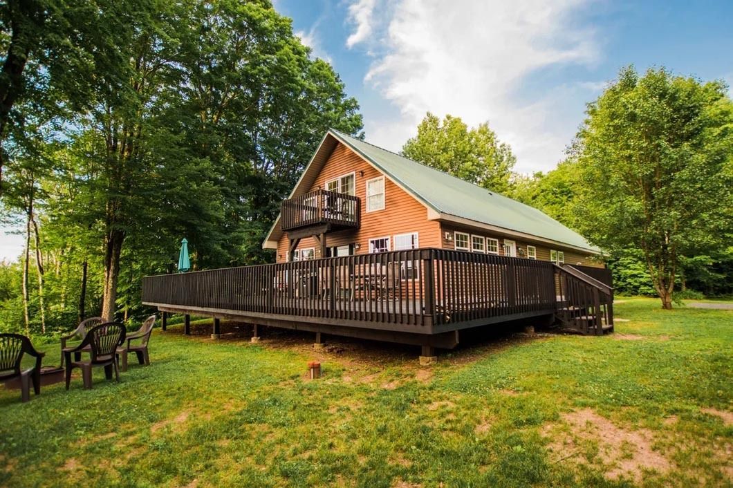A cabin with a large deck and chairs in front of it.