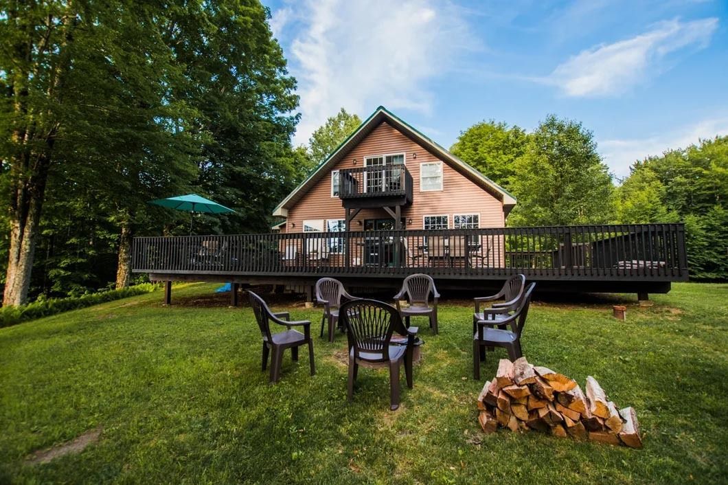 A house with a large deck and a fire pit in front of it.