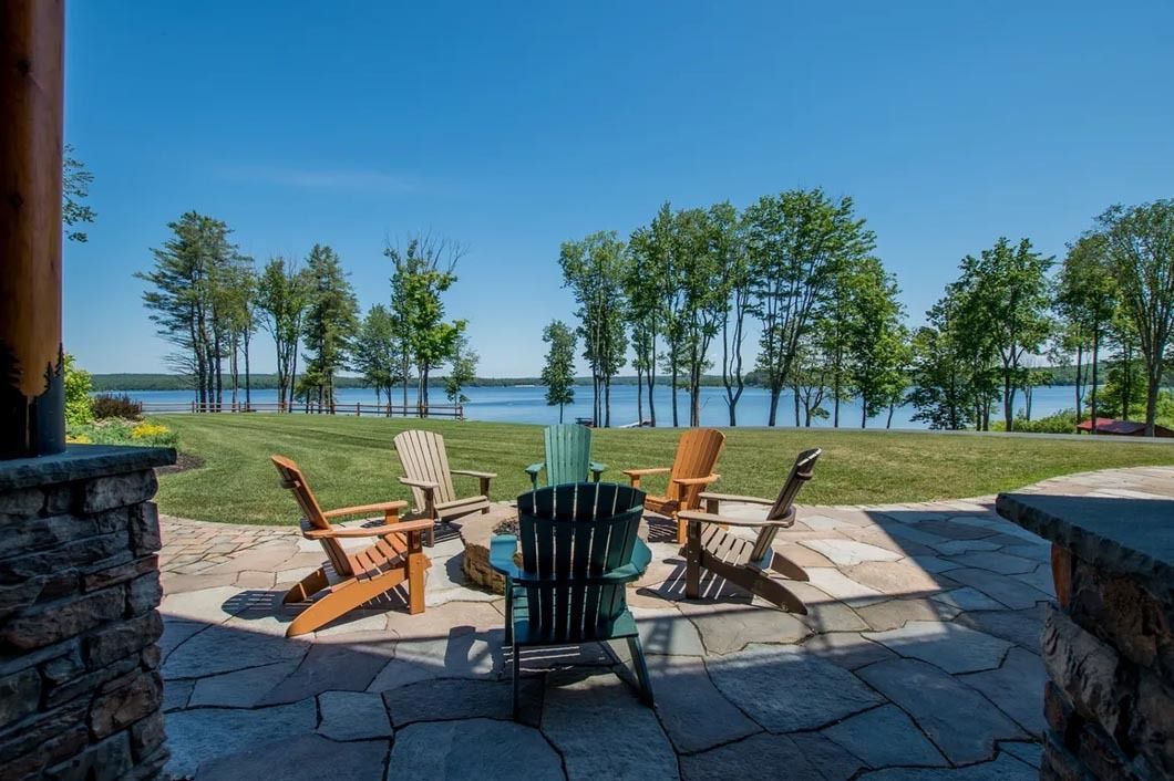 A group of chairs are sitting on a patio overlooking a lake.