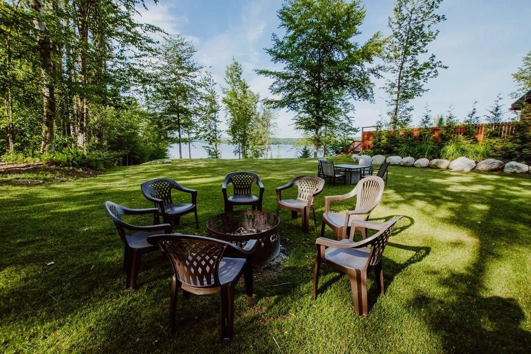 A group of chairs are sitting around a fire pit in the grass.