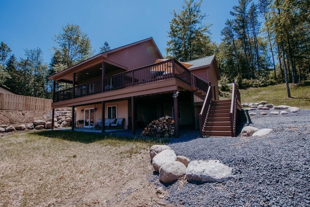 A large house with a large deck in the middle of a forest.