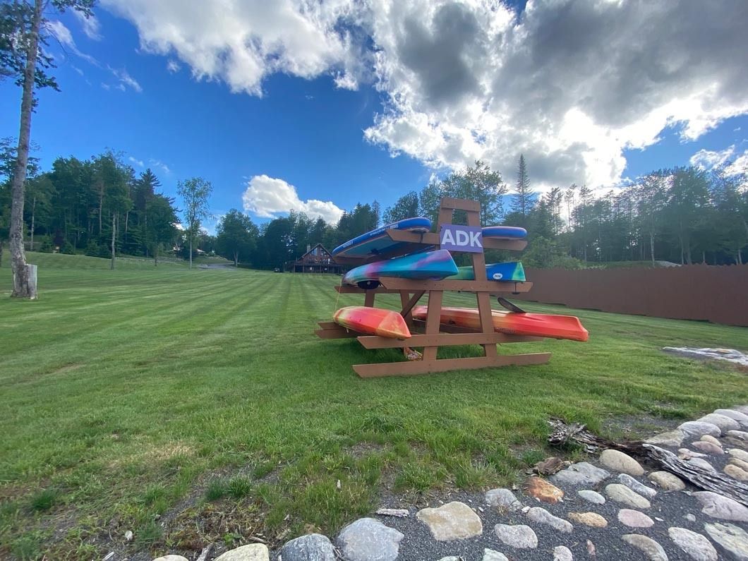 A row of kayaks sitting on top of a wooden rack in a grassy field.
