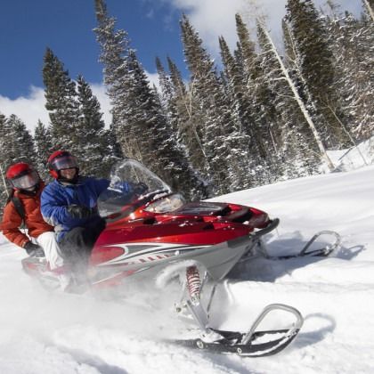 Two people are riding a red snowmobile in the snow
