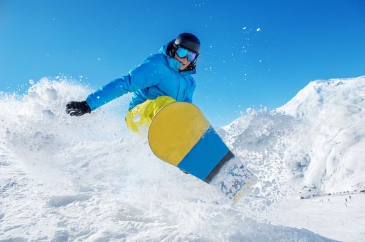 A man is riding a snowboard down a snow covered slope.