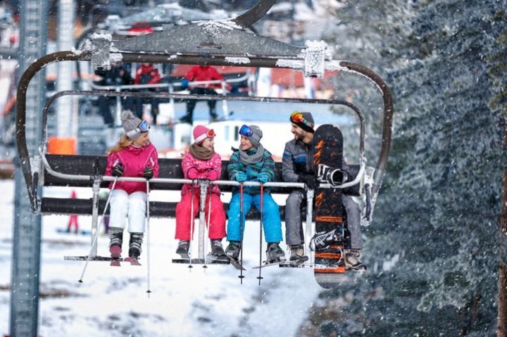 A group of people are riding a ski lift in the snow.