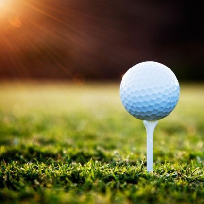 A golf ball is sitting on a tee in the grass.
