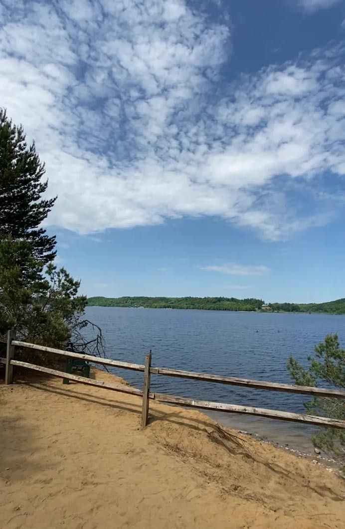 A wooden fence surrounds a lake on a sunny day.