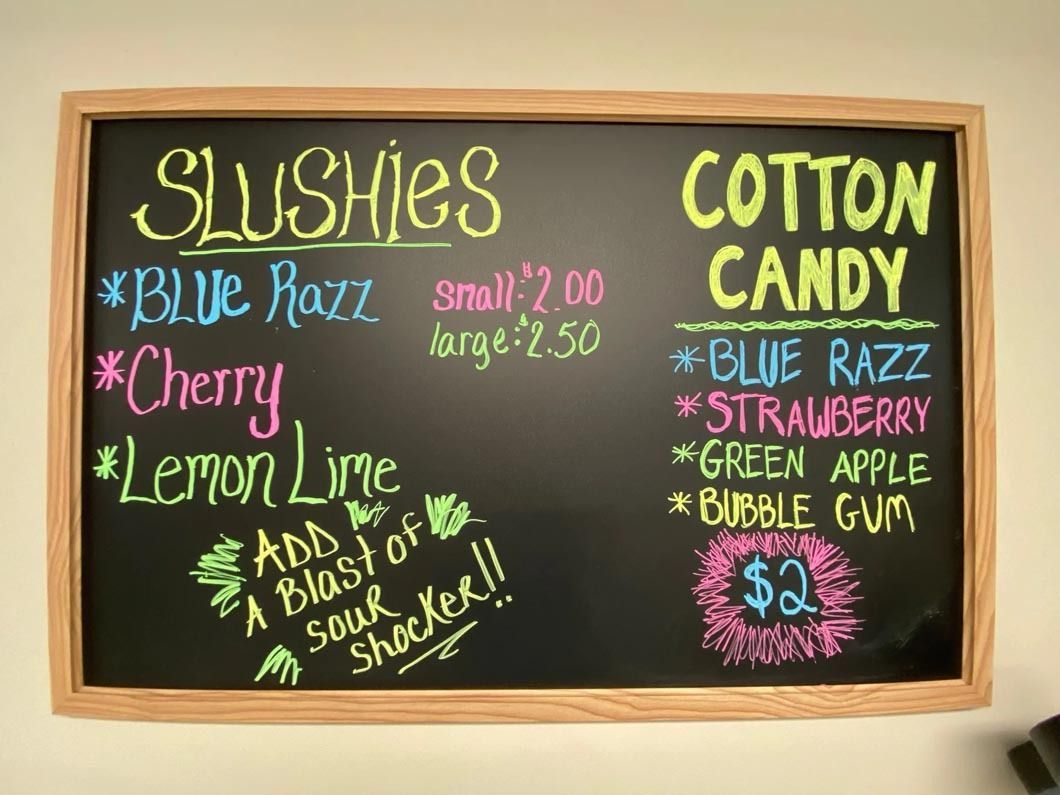 A chalkboard advertising cotton candy and slushies