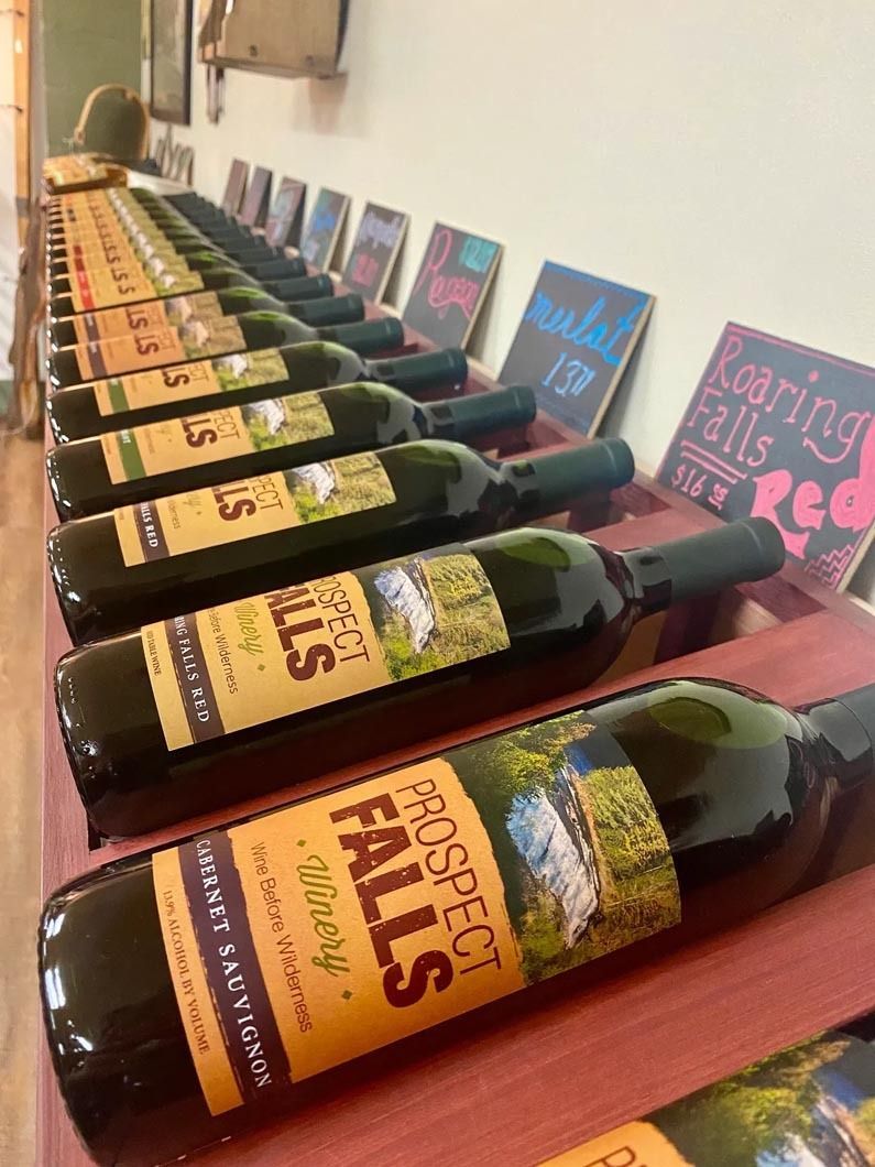 A row of bottles of prospect falls wine are lined up on a shelf.