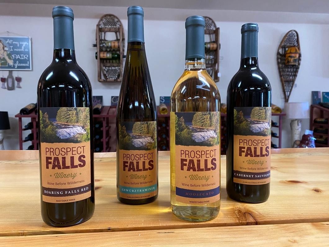 Four bottles of wine are sitting on a wooden table.
