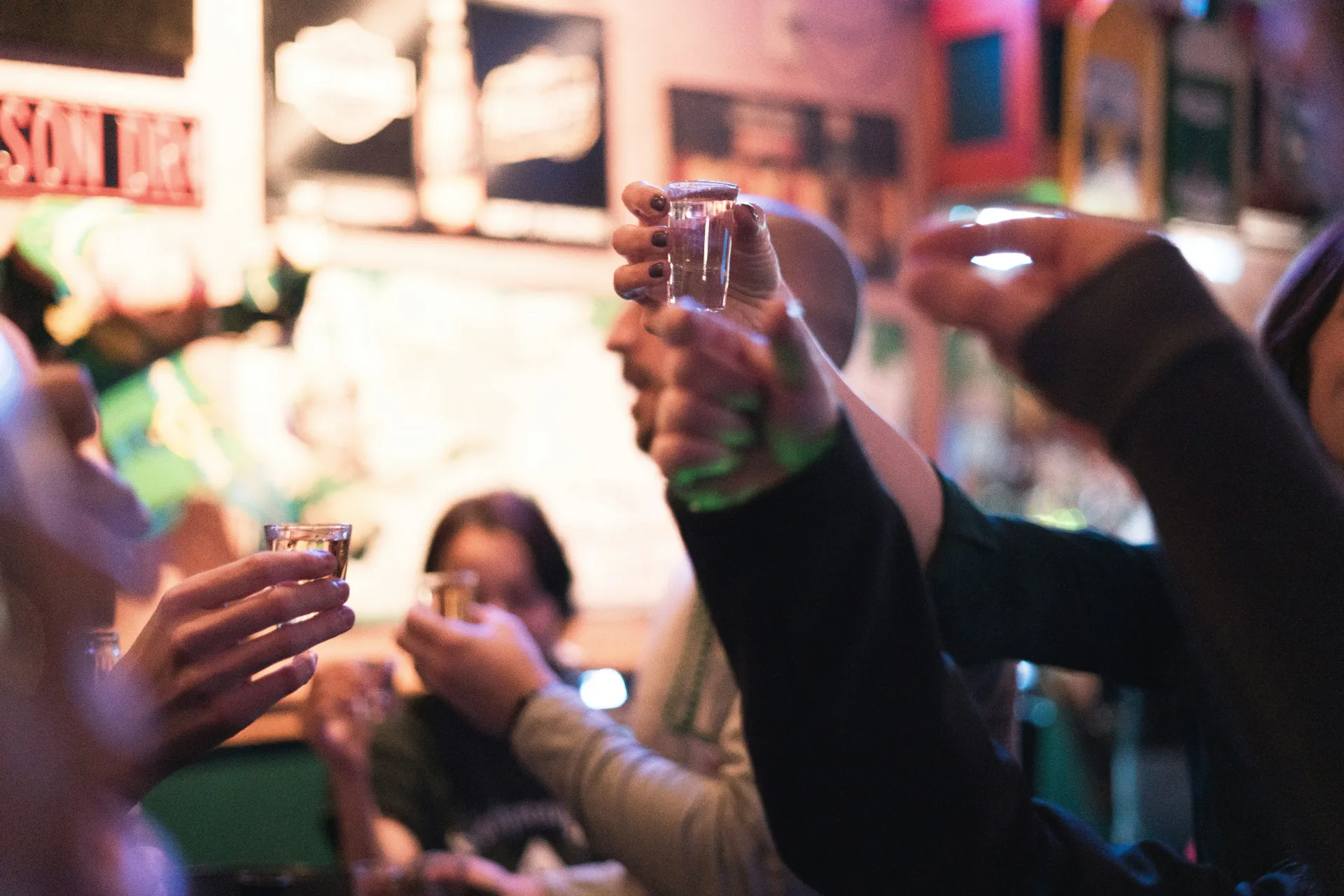 People holding and cheering shot glasses.