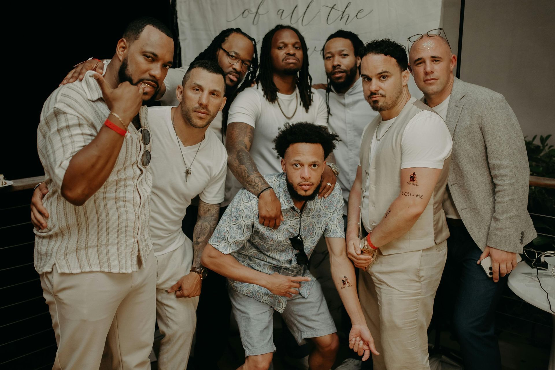 Group of men in beigh clothing posing for a photo.