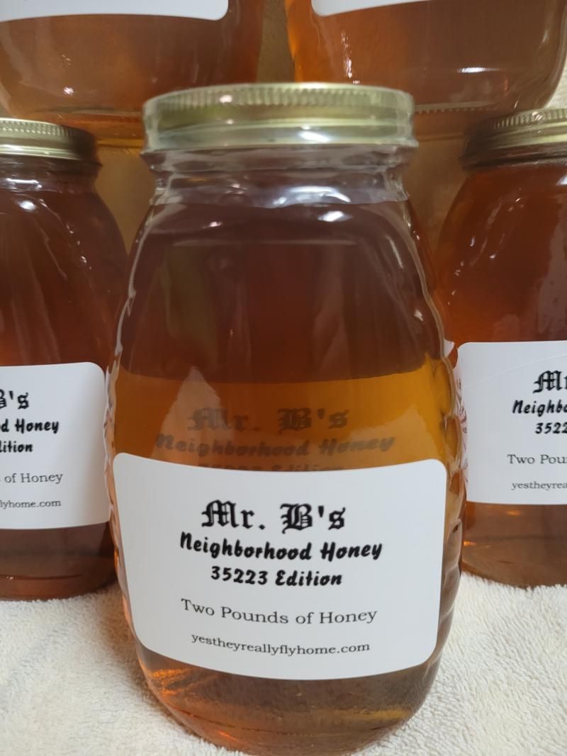 Honey jar labeled “Mr. B’s Neighborhood Honey” on a shelf, with other jars in the background