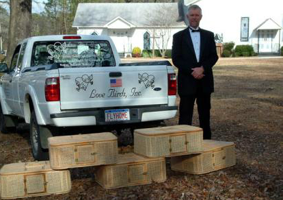 Man standing beside a white pickup with wooden blocks stacked in front, outdoors at a church