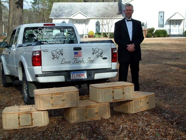 Man in tuxedo beside silver pickup truck with several wicker baskets in a yard