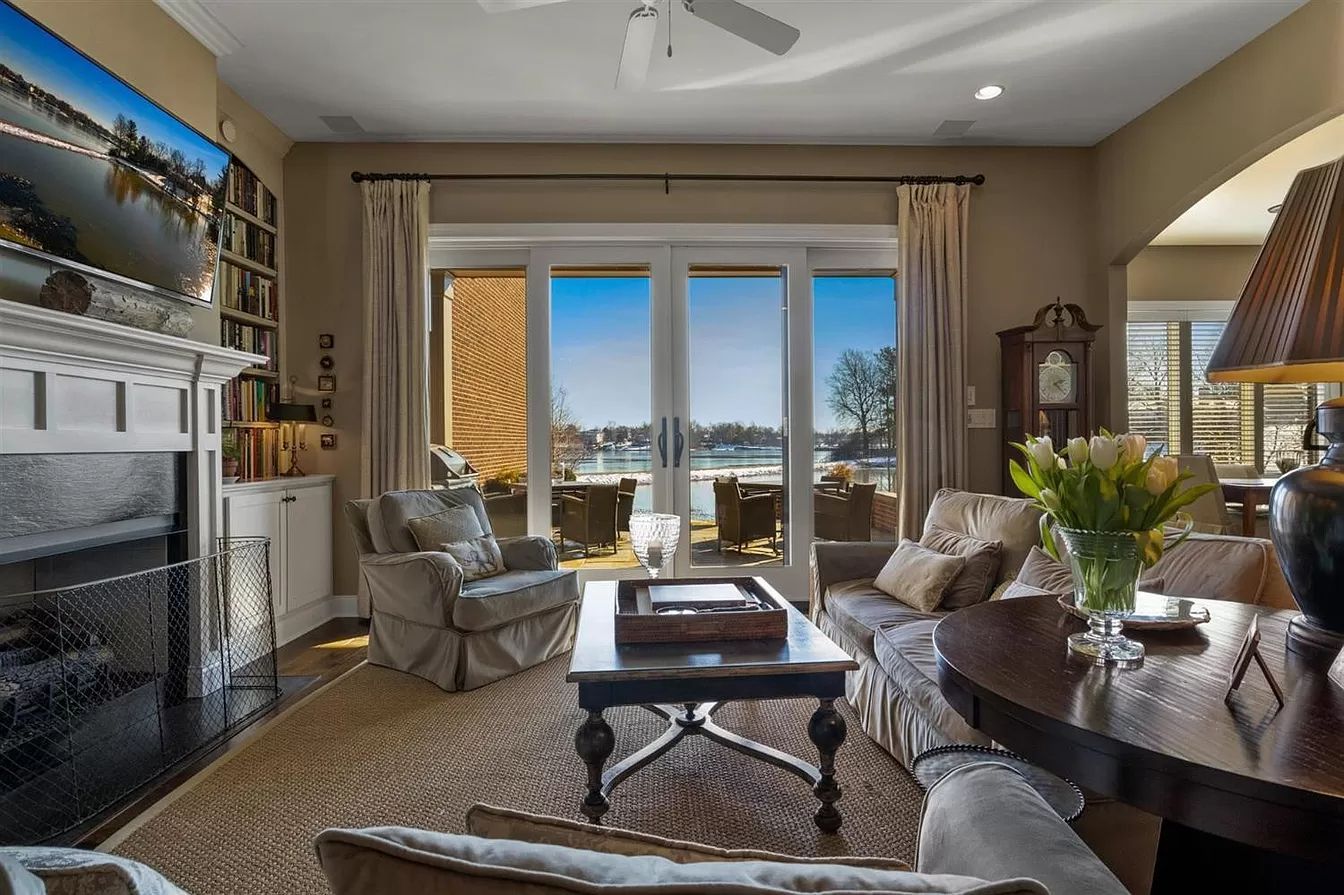 Elegant living room with stone fireplace, large windows, and a mountain view at sunset