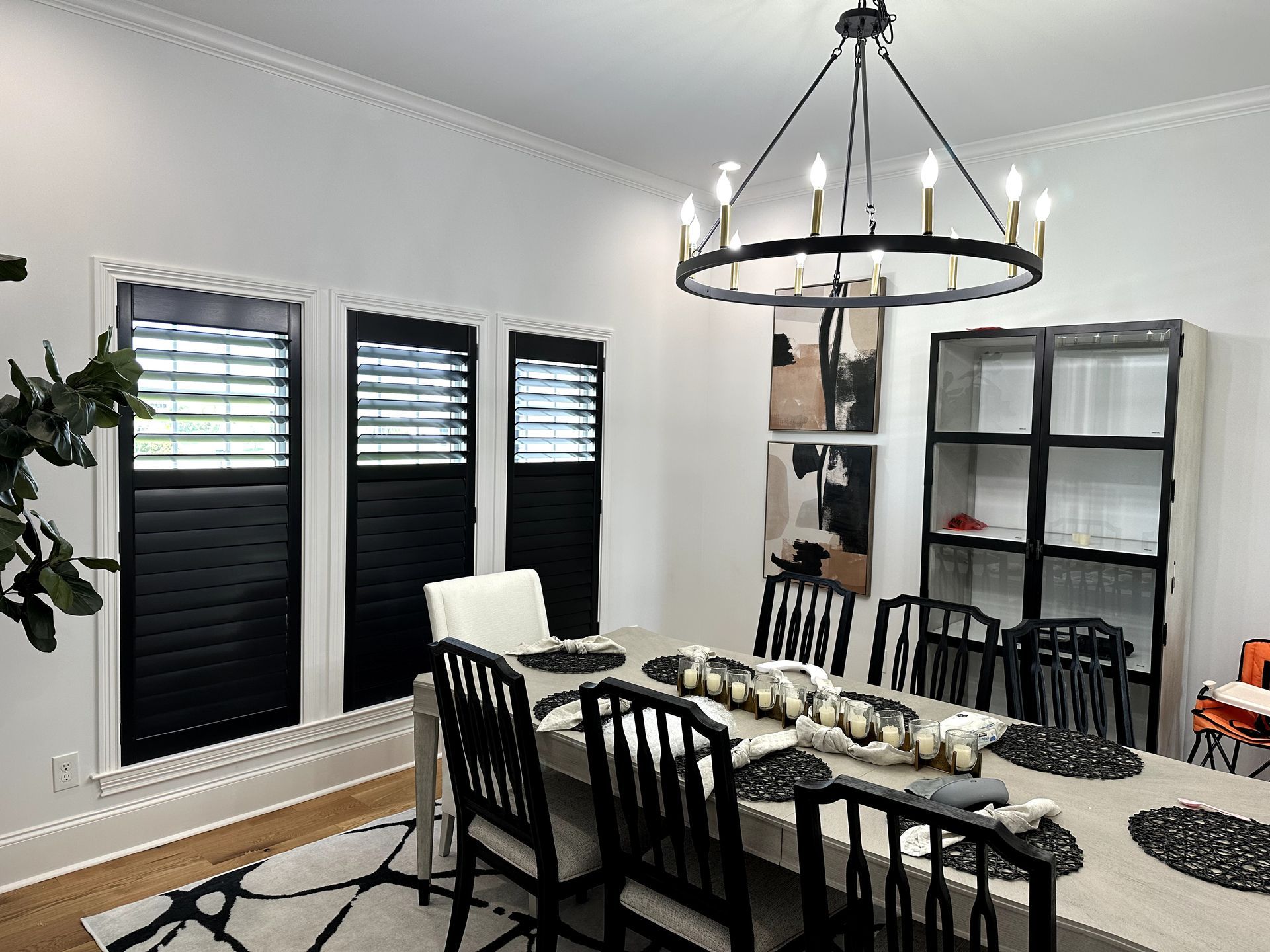 Dining room with black shutters, chandelier, table set for a meal.