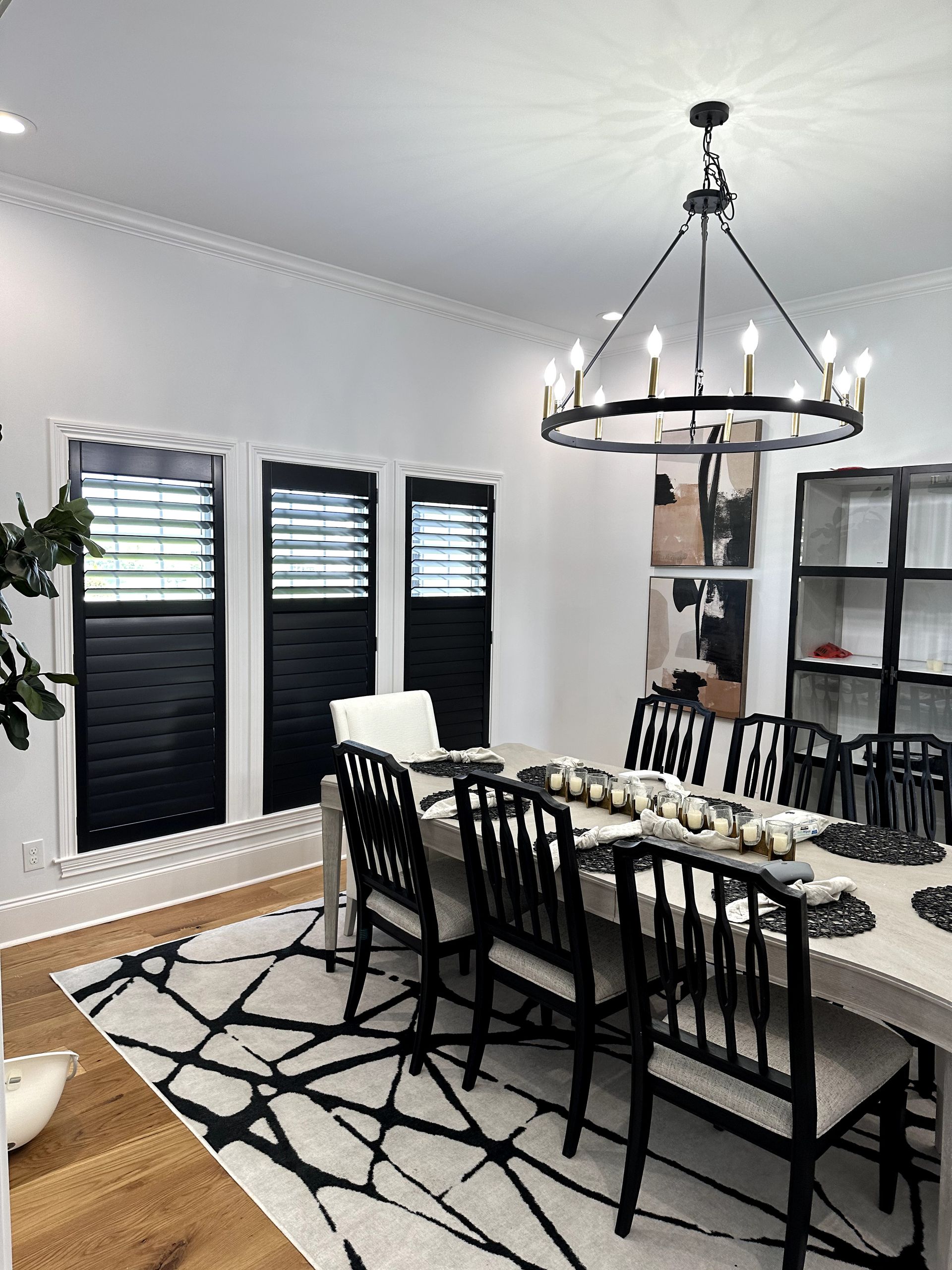 Elegant dining room with black and white decor; large table set for dinner under a chandelier.