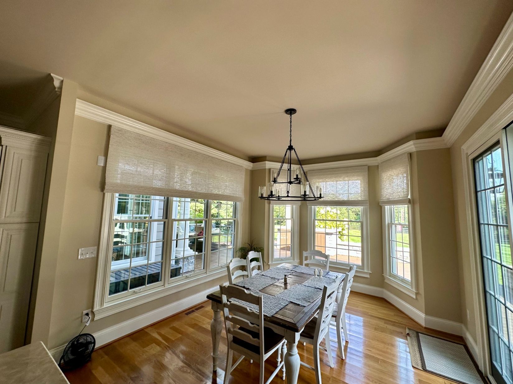 Bright dining room with large windows with motorized solar shades, chandelier, and a table set for six on hardwood floors
