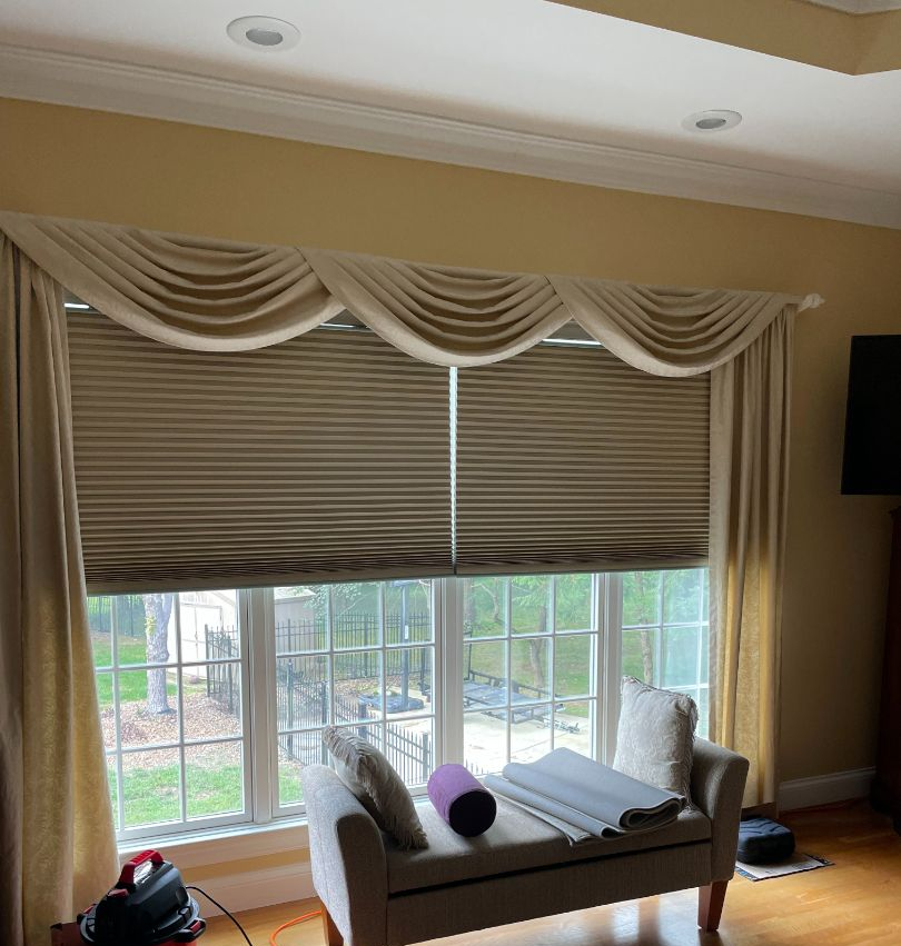 Dining room with a table, white chairs, chandelier, and Roman shades.