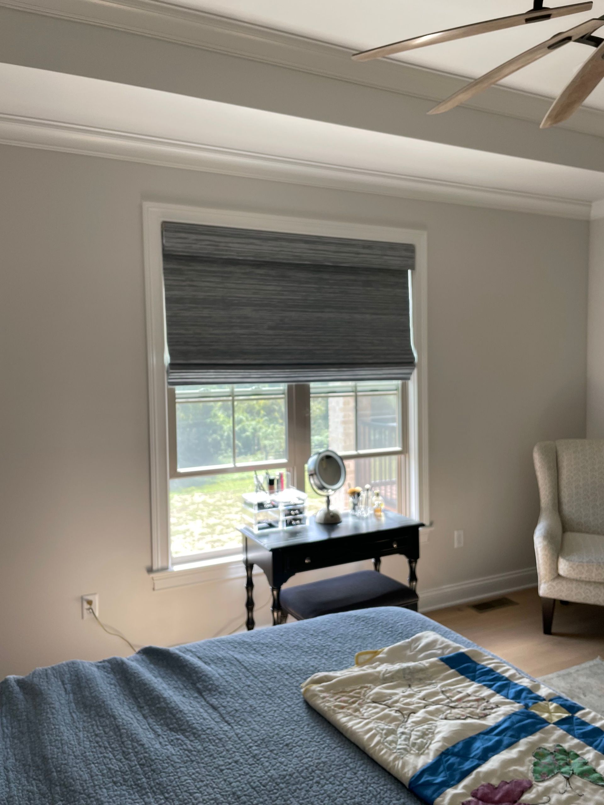 Bedroom with bed, window, and vanity desk in a softly lit gray room