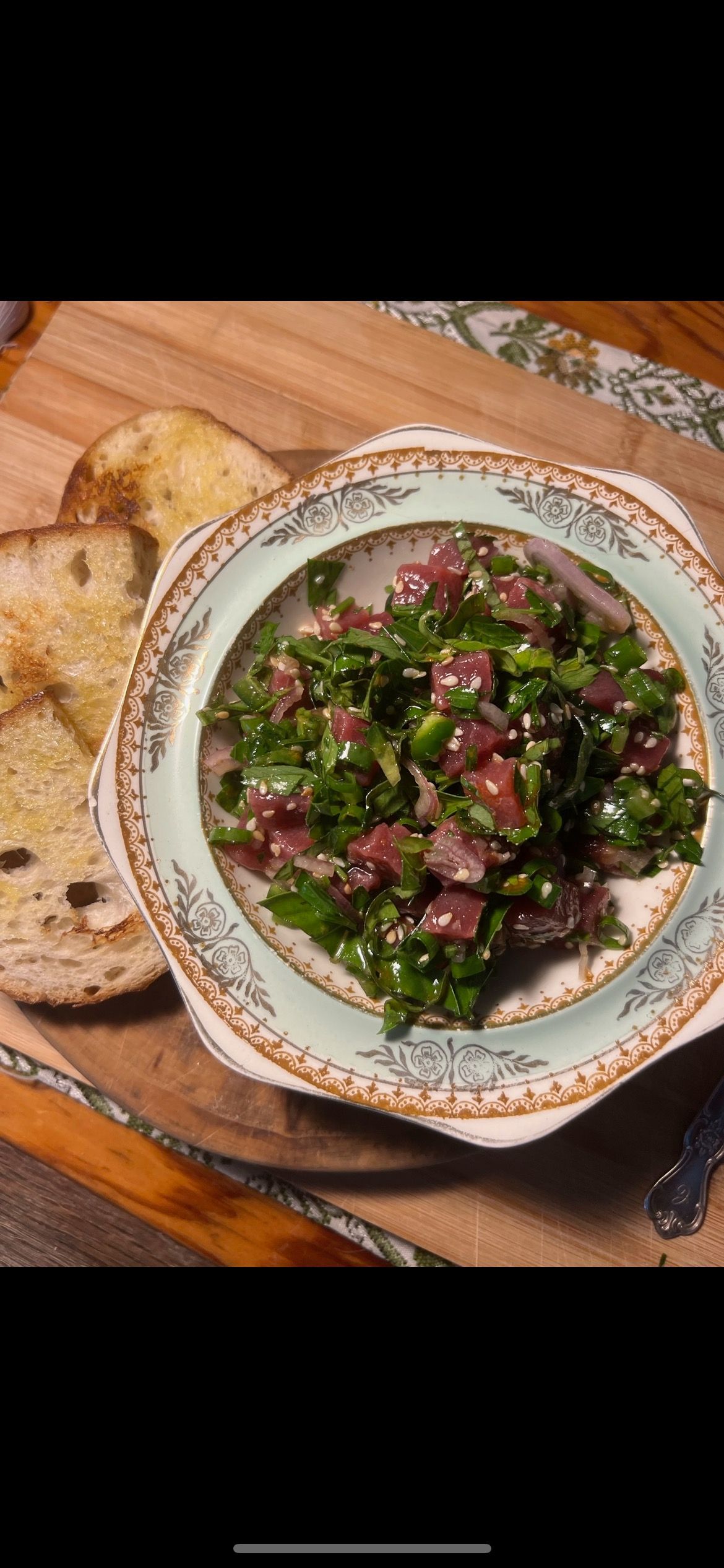 Bowl of chopped salad with toasted bread on a wooden board.