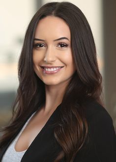 A woman with long dark hair is smiling and wearing a black jacket.