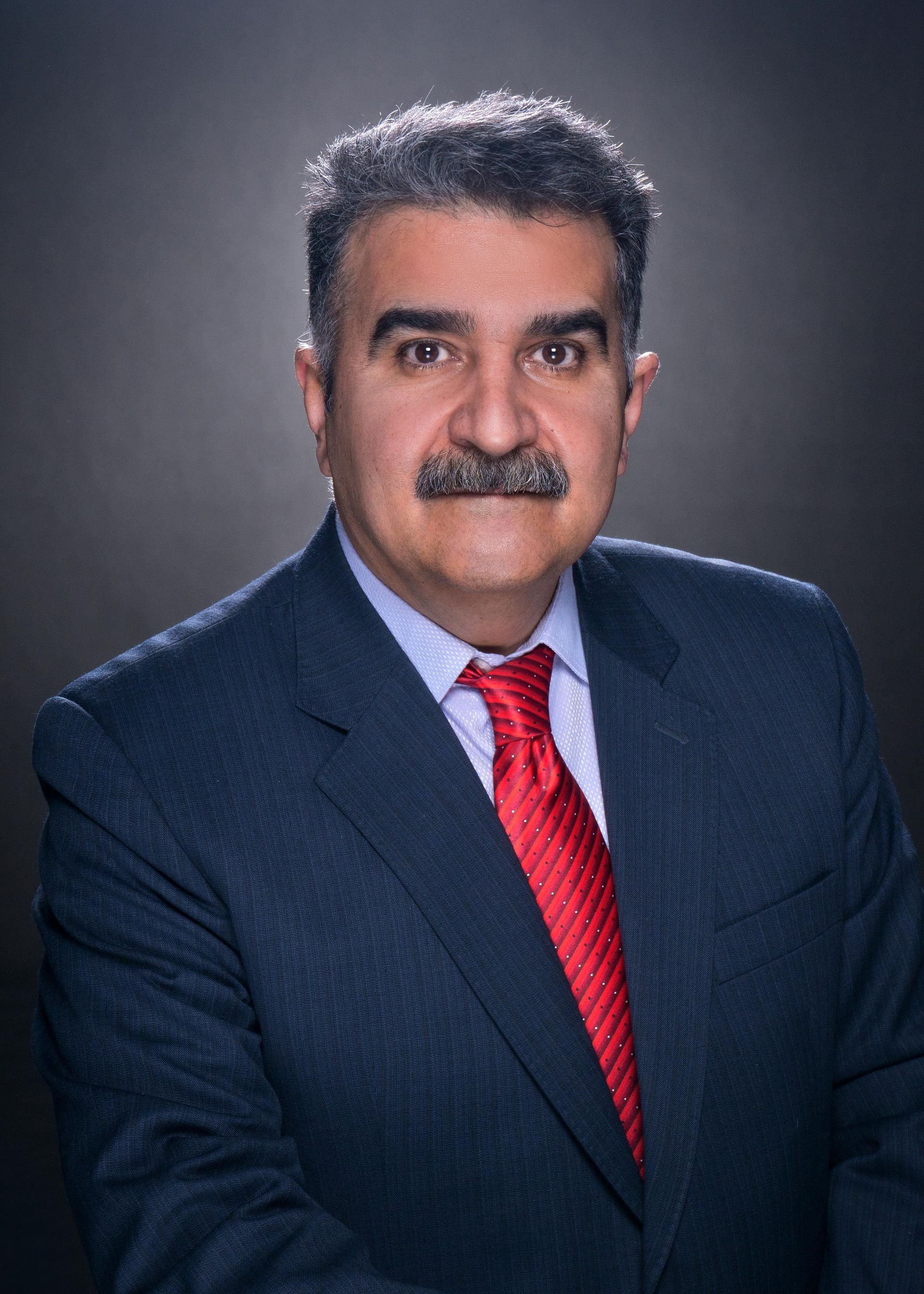 A man with a mustache is wearing a suit and tie.