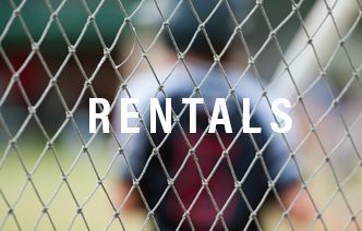 A person is behind a chain link fence with the word rentals written on it.
