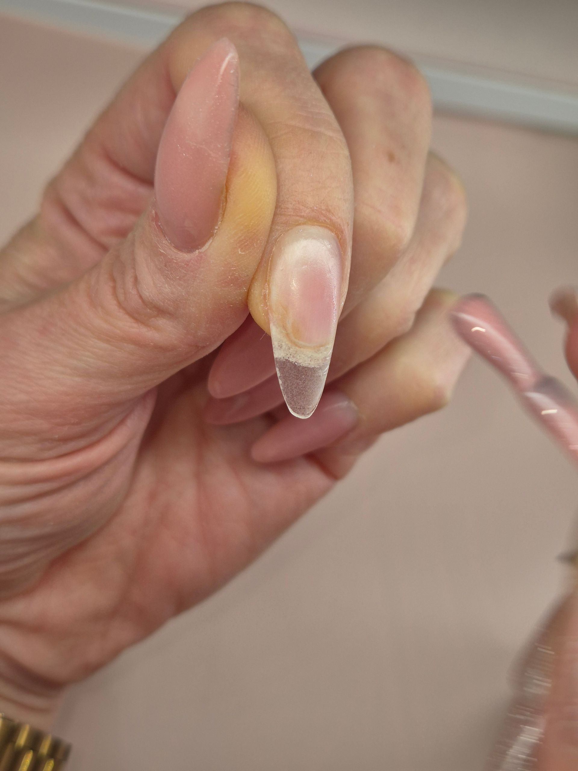 Handen met verzorgde nagels, in diverse pastelkleuren en met verschillende designs, naast flesjes nagellak.