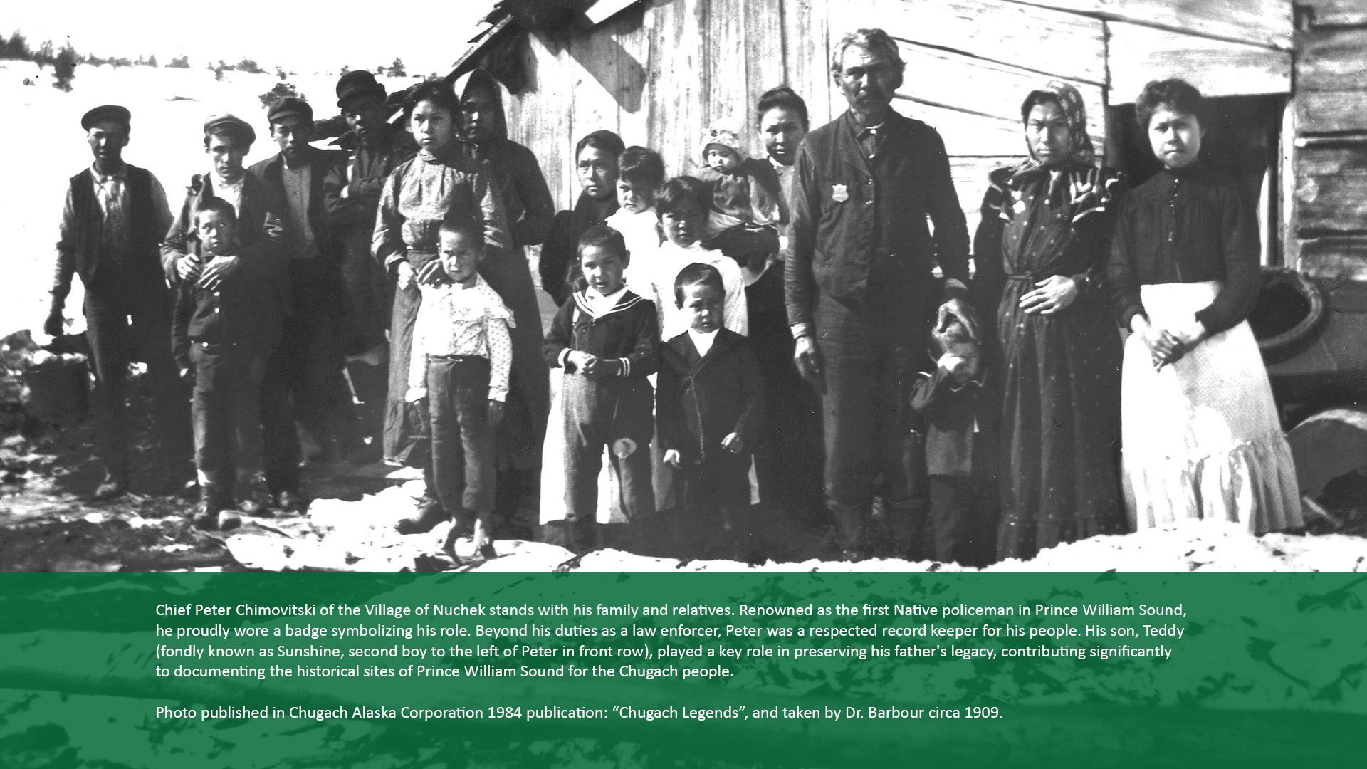 Group of people standing in front of a building. Many children and adults are posed together, possibly a family.