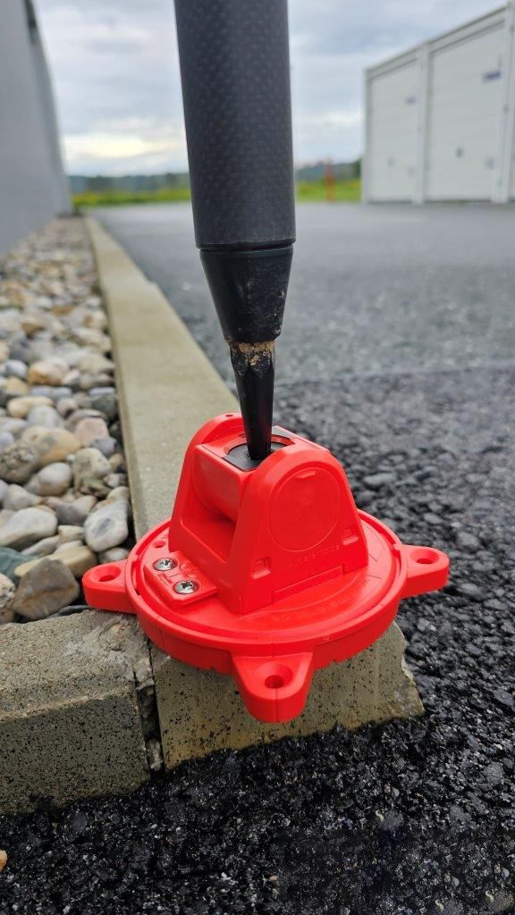 A screwdriver is being used to attach a red object to a pole.